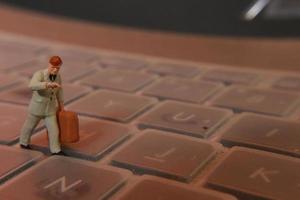 een miniatuur figuur van een kantoor arbeider draag- een aktentas wandelen tussen de toetsenborden. foto