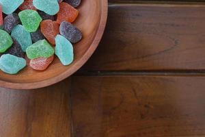 een dichtbij omhoog van kleverig snoepjes van divers kleuren en fruit smaken geserveerd in een houten schaal. foto