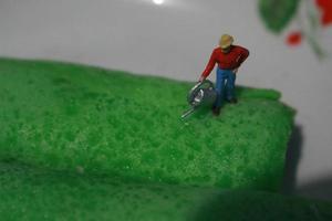 miniatuur figuren van boeren Bij werk Aan groen pannenkoek broodjes. concept van landbouw foto. foto