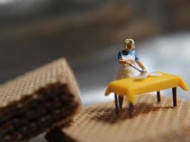 een miniatuur figuur van een vrouw Koken Aan een chocola wafeltje. foto