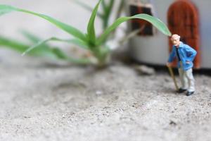 miniatuur figuur van een opa wie is aan het wachten in voorkant van de huis. foto