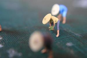 miniatuur figuren van boeren werken Aan een snijdend mat. concept van landbouw foto. foto