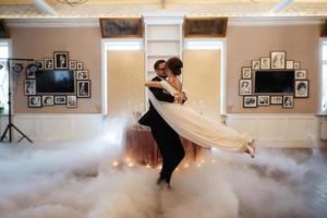 de eerste dans van de bruid en bruidegom binnen een restaurant foto