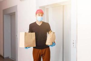 koerier in beschermend masker en medisch handschoenen levert meenemen voedsel. levering onderhoud onder quarantaine, ziekte uitbraak, coronavirus covid-19 pandemisch conditie. foto