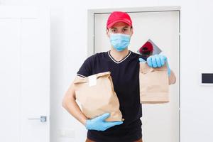 levering Mens Holding papier zak met voedsel Aan wit achtergrond, voedsel levering Mens in beschermend masker foto