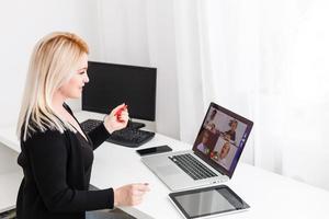 docent, tutor of professor met koptelefoon, laptop en camera in haar kantoor uitleggen iets Bij een online les of video lezing, webinar foto