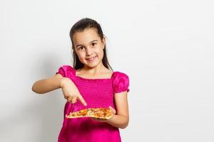 schattig weinig Indisch Aziatisch meisje kind aan het eten smakelijk pizza. staand geïsoleerd over- wit achtergrond. foto