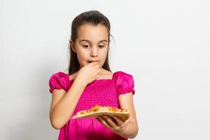 schattig weinig Indisch Aziatisch meisje kind aan het eten smakelijk pizza. staand geïsoleerd over- wit achtergrond. foto