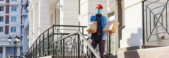 levering Mens Holding papier zak met voedsel Aan wit Ingang van huis achtergrond , voedsel levering Mens in beschermend masker foto