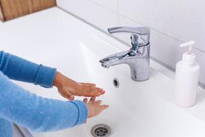 klein kind het wassen handen met zeep en water, detail foto