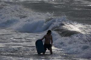 surfers krijgen klaar naar invoeren de water en wandelen met de bord langs de oever. foto