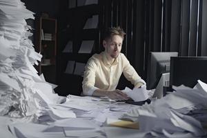 homme au milieu de aambeien de papiers sur zoon bureau foto