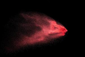 rood stof deeltjes explosie Aan zwart achtergrond.rood poeder plons. foto