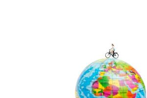 miniatuurreiziger met een fiets op een wereldbol op een witte achtergrond foto