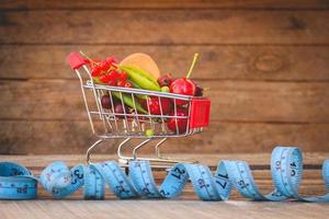 boodschappen doen kar met fruit, bessen en plakband lijn Aan oud hout achtergrond. afgezwakt afbeelding. foto