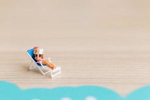 miniatuurmensen die op een strand, zomerconcept zonnebaden foto