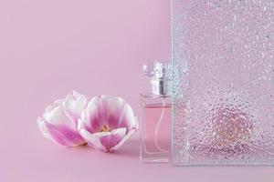 creatief samenstelling met een mooi fles van vrouwen parfum, reliëf glas en delicaat voorjaar bloemen. voorkant visie. lila achtergrond. foto