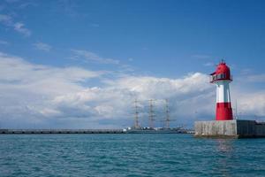 zeegezicht met vintage zeilboot en een vuurtoren met een bewolkte blauwe hemel in Sochi, Rusland foto