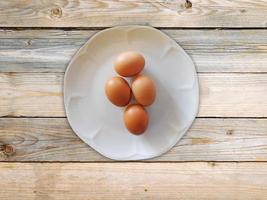 bruine eieren op een witte plaat op een houten tafel achtergrond