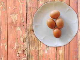 bruine eieren op een witte plaat op een houten tafel achtergrond