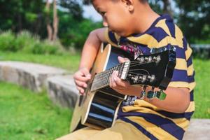 jongen die een gitaar buiten speelt foto