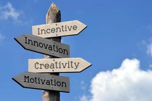 creativiteit, innovatie, beloning, motivatie - houten wegwijzer met vier pijlen, lucht met wolken foto