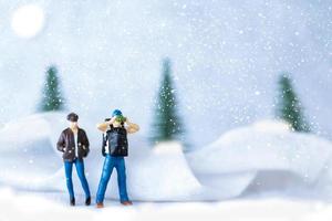 miniatuur mensen backpacker reizen in winter tijd foto