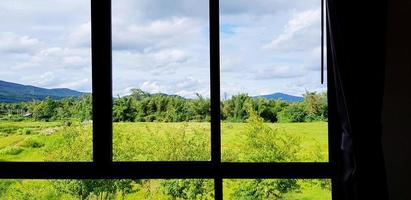 silhouet van lijn van venster en gordijn met groen veld, berg, blauw lucht en wolken visie. schoonheid van natuur, landschap en natuurlijk kader foto