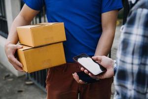 levering Mens met beschermend masker en handschoenen leveren pakketten gedurende vergrendeling en pandemisch en Holding mobiel contactloos betaling machine foto