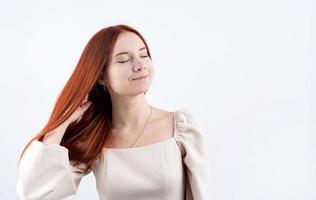 portret van een jong mooi vrouw aanraken haar rood haar- Aan wit achtergrond, kopiëren ruimte foto