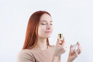 gelukkig jong vrouw ruiken parfum, Holding glas fles geïsoleerd Aan wit achtergrond foto