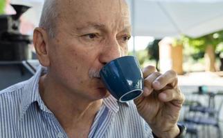 ouderen Mens drinken espresso koffie Bij een buitenshuis cafe foto