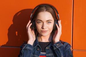portret gelukkig glimlachen jong vrouw met hoofdtelefoons luisteren naar muziek- Aan oranje foto