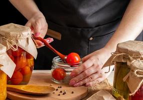 een vrouw fermenteert groenten. ingelegde tomaten in potten. behoud van de herfstoogst. biologisch voedsel. foto