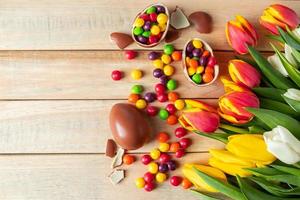 mooie rode en gele tulpen voor paasvakantie. chocolade-eieren en snoepjes op een houten achtergrond.