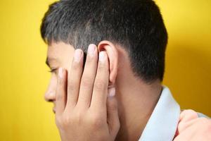 tiener met oorpijn bij het aanraken van zijn pijnlijke oor, foto