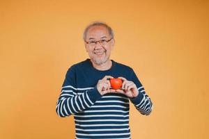 senior mannetje Holding hart liefde emotie verzekering concept Aan kleur achtergrond. foto