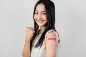 gelukkig jong vrouw tonen zege teken na krijgen een vaccin. tonen schouder met verband na ontvangen vaccinatie, kudde immuniteit, kant effect, booster dosis, vaccin paspoort en coronavirus foto