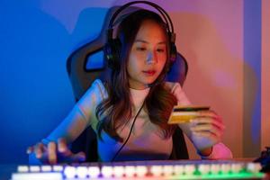 top omhoog online spel met credit kaart concept. gamer en e-sport online van Aziatisch vrouw spelen online computer video spel met verlichting effect, uitzending streaming leven Bij huis. gamer en e-sport gaming foto