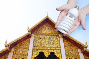 energie besparing concept, vrouw hand- Holding licht lamp Aan tempel achtergrond, ideeën licht lamp in de hand- foto