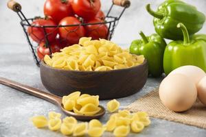 ongekookte schelpvormige pasta met rauwe kippeneieren op een stenen tafel foto