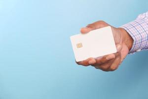 iemands hand met creditcard tegen blauwe achtergrond foto