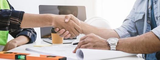 dichtbij omhoog hand- van groep, team jong Mens aannemer, ingenieur handdruk met vennootschap, klant na overeenkomst naar werk samen Bij de plaats, werkplek. bedrijf succes concept. foto