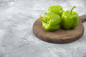 verse groene paprika geplaatst op een houten ronde plank foto