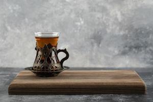 een glazen kopje hete thee op een houten snijplank foto