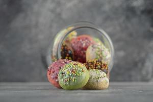 een glazen pot vol kleine kleurrijke donuts