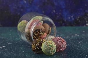 een glazen pot vol kleine kleurrijke donuts