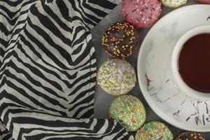 kleurrijke zoete kleine donuts met hagelslag en een kopje thee foto