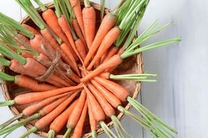 vers wortel, baby wortel in mand Aan wit hout achtergrond foto