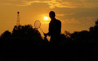 silhouetten Mens is Holding de shuttle en de badminton racket foto